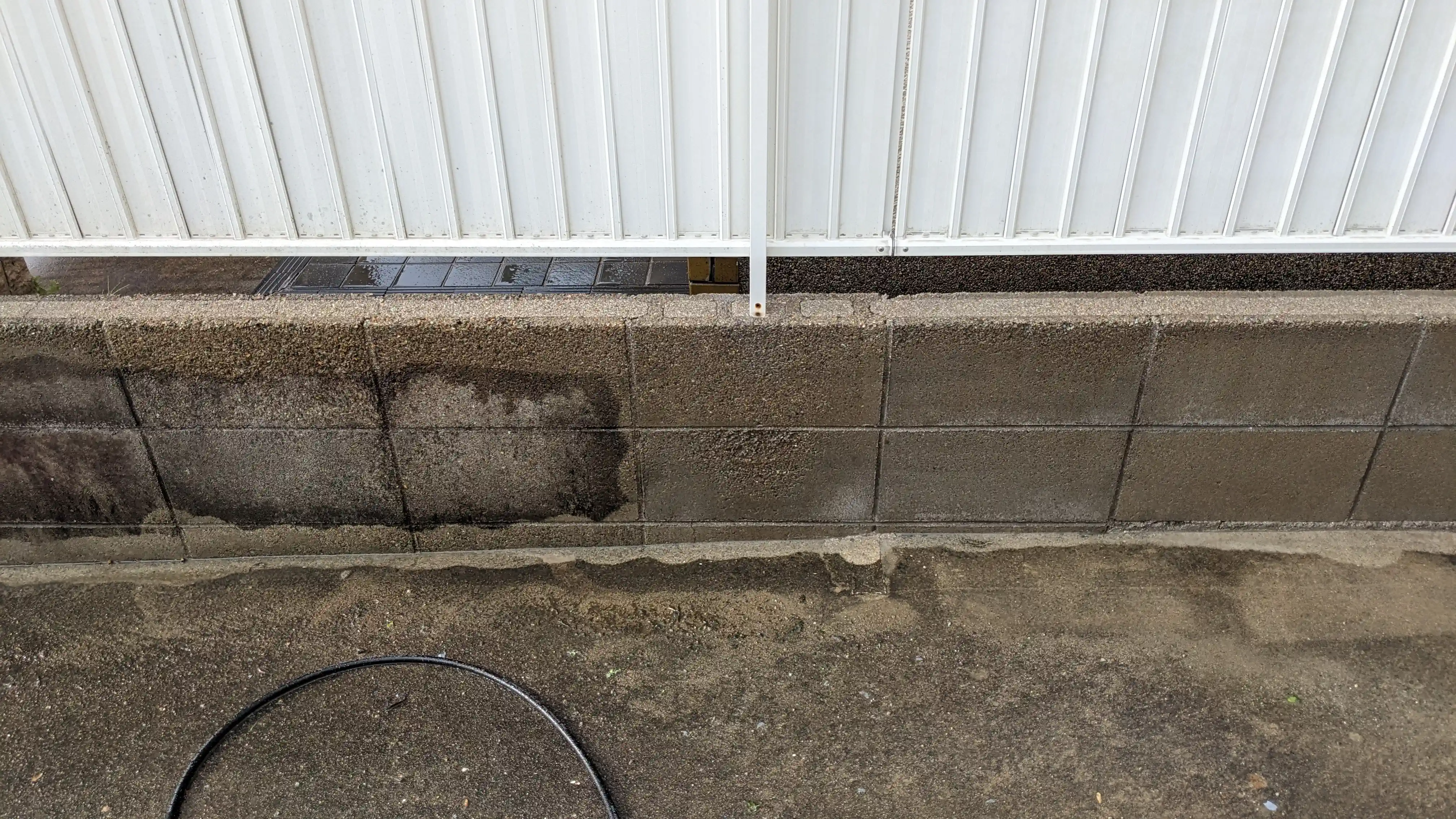 Boundary block wall showing a pressure washing test patch beside a Japanese house